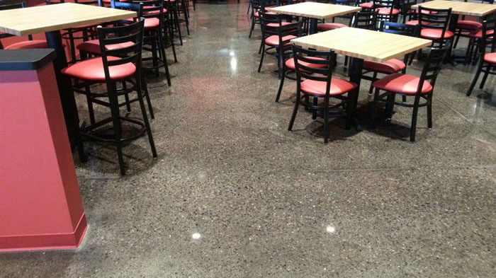 speckled concrete floor with restaurant tables.