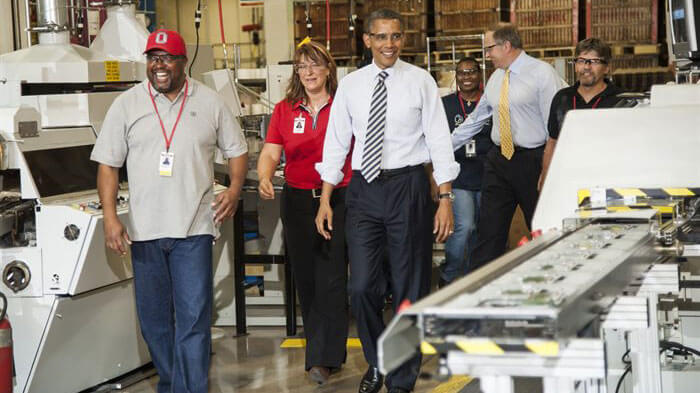President Obama walking on concrete floor with Honeywell employees.